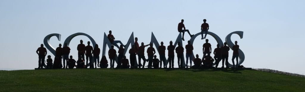 Letras corpóreas en grupo con personas en el fondo, representando "Nosotros".